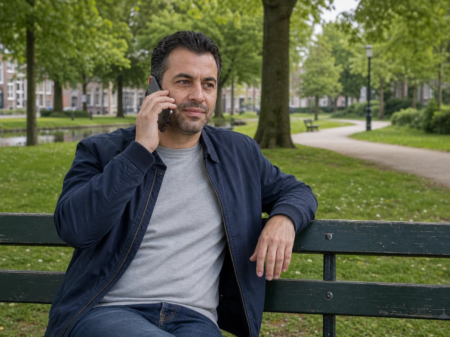 A man sits on a park bench with a mobile phone.